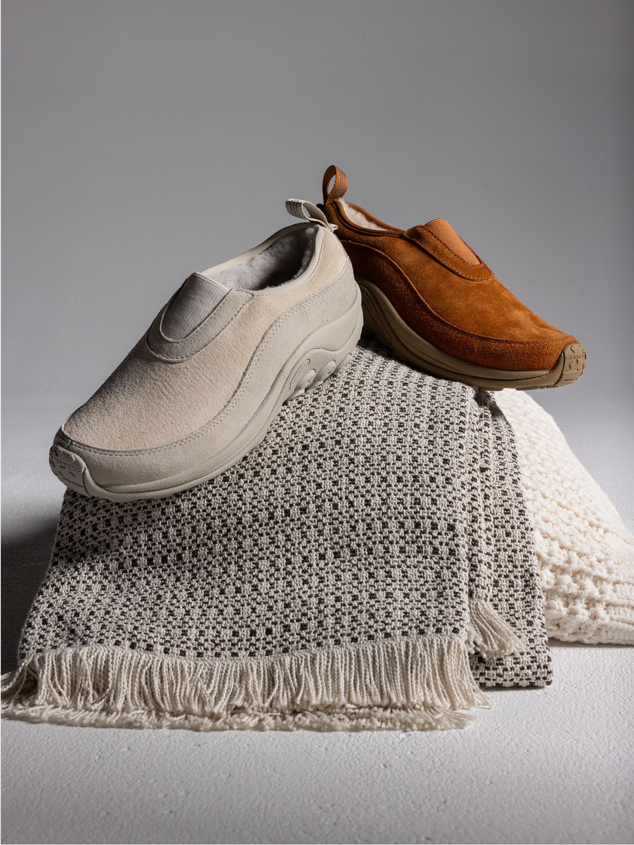 Jeune fille assise sur un rocher, souriante, portant des chaussures Merrell colorées.